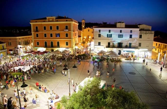 La piazza di Santa Teresa Gallura la sera, con i tavolini dei bar e la gente in giro